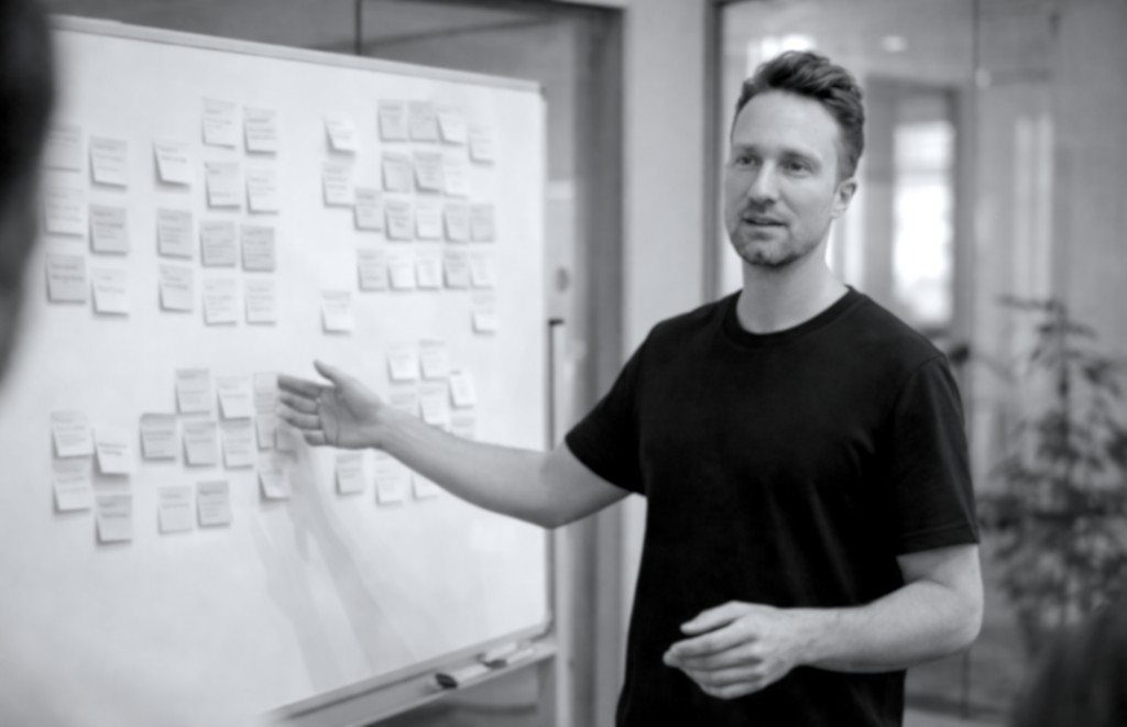 Product advisor presenting at a whiteboard covered in sticky notes during a strategy session
